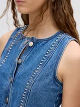 Chaleco de denim liviano con cierre frontal de botones metálicos, detalle de apliques metálicos verticales y ruedo con terminación desflecada.