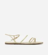 Sandalia plana dorada con tiras finas y cierre con hebilla en el tobillo.