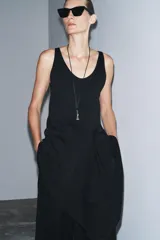 Collar de cordón negro con colgante metálico plateado en forma de pieza de ajedrez (caballo). Cierre con lazada y acabados con piezas metálicas labradas.