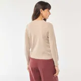 Cárdigan de punto fino color beige, con cuello redondo, manga larga y cierre frontal con botones a tono.