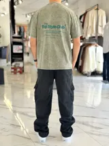 Remera oversize gris con efecto acid wash, de mangas cortas y cuello redondo, con estampado tipográfico blanco en la espalda.