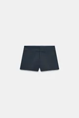 Shorts de tiro medio con bolsillos laterales en el delantero y falsos bolsillos con solapa en la parte trasera. Presenta cierre frontal con cremallera y ganchos metálicos.