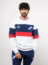 Buzo de felpa con cuello redondo, diseño de bloques de color en blanco, azul y rojo. Presenta el logo de Umbro y el escudo del Club Nacional de Football bordados en el pecho.
