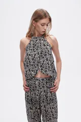 Top cropped de viscosa con estampado paisley en tonos negro y beige, diseño sin mangas con cuello halter y detalle de lazada.