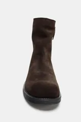 Botín plano de mujer confeccionado en serraje color marrón oscuro, con caña baja, tirador trasero y cierre mediante cremallera lateral. Presenta punta redonda y suela plana.