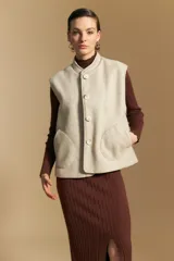 Chaleco de paño color marrón oscuro, de silueta recta y diseño minimalista. Presenta cuello a la base, cierre frontal con botones claros y bolsillos aplicados.