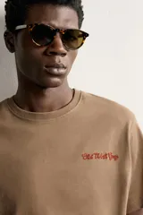Camiseta regular fit de color marrón, con cuello redondo, manga corta y texto bordado a contraste en el pecho.