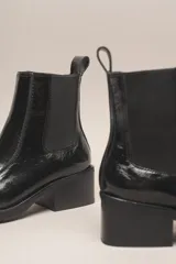 Bota Chelsea de cuero charol negro, con elástico lateral, punta cuadrada y taco bajo.