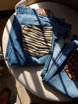 Pantalón de jean azul con bolsillos traseros desmontables con estampado animal print. Los bolsillos se sujetan al pantalón con remaches metálicos.
