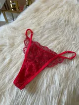 Tanga de encaje rojo con diseño regulable en los laterales y corte media less, con refuerzo de algodón en la entrepierna.
