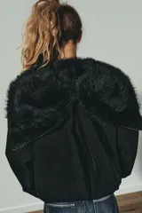 Cazadora acolchada de color negro con capucha, cuello subido y cierre frontal con cremallera y botones metálicos. Presenta manga larga con puño elástico, bolsillos delanteros y bajo ajustable con stoppers.