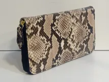 Billetera rectangular con cierre perimetral, confeccionada en cuero con estampado de piel de serpiente. Cuenta con múltiples compartimentos internos para tarjetas, documentos y billetes, además de un bolsillo interior con cierre para monedas.