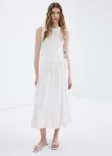 Vestido midi color blanco con diseño evasé, cuello redondo y sin mangas de tirante ancho. Cuenta con un detalle de pañuelo bordado en la cintura con cierre de cremallera lateral.