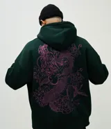 Buzo con capucha de color verde oscuro, confeccionado en tejido con felpa. Presenta un diseño estampado en la espalda con motivos de dragón y flores en color fucsia.
