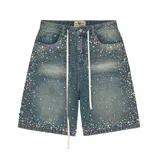 Short de jean estilo baggy con lavado azul, decorado con múltiples cristales y piedras de colores en toda la superficie. Presenta cordones largos en la cintura y cierre frontal.