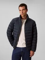 Campera puffer de peso medio Calvin Klein, con diseño acolchado, cuello alto y cierre frontal de cremallera. Presenta un logo sutil estampado en el pecho y está confeccionada en nailon reprocesado.