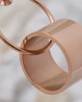 Caravanas colgantes de acero con diseño circular minimalista, compuestas por un aro superior y un cilindro inferior. Acabado en tono oro rosado.