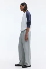 Pantalón jogger de punto de algodón gris melange, de corte relajado y perneras rectas con pliegue frontal cosido. Presenta cintura elástica con cordón ajustable, bolsillos laterales y falsas braguetas decorativas.