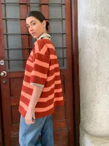 Remerón de algodón a rayas horizontales color naranja y salmón, con cuello tipo polo y mangas cortas.