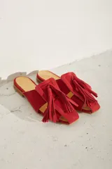 Zueco plano de cuero color dorado, con diseño de tiras anchas entrelazadas en el empeine y punta cuadrada.