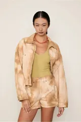 Chaqueta de algodón con estampado tie-dye en tonos beige y marrón claro, de corte recto, con cuello clásico, cierre frontal con cremallera, mangas largas y bolsillos frontales.