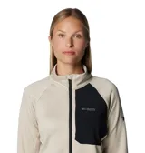 Campera técnica de mujer con cierre frontal completo, confeccionada en tejido transpirable de secado rápido. Presenta cuello alto, bolsillo con cierre en el pecho en contraste de color, y puños con orificios para los pulgares. El diseño incluye ribetes elásticos en puños y dobladillo para mayor ajuste.