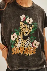 Remera de algodón con efecto lavado, cuello redondo y mangas cortas. Presenta un estampado frontal con un guepardo rodeado de flores y la palabra 'SAVAGE' en letras doradas.