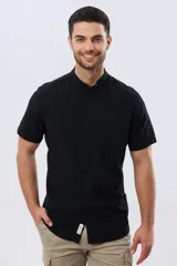 Camisa de lino y algodón de manga corta, color negro, con cuello mao, cierre frontal con botones y bolsillo ojal en el pecho.