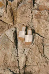 Sandalias con base marrón y tira ancha de cuero color dorado.