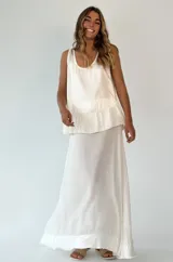 Conjunto de top y falda larga color blanco. El top es musculosa con volados en el ruedo y la falda es larga y recta.