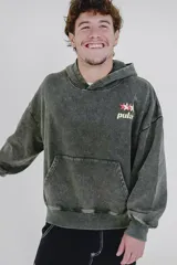 Canguro gris oscuro con efecto lavado (acid wash) y capucha. Presenta un pequeño estampado frontal con estrellas y la palabra "pulau" en tonos rosado y amarillo. Tiene bolsillo canguro y puños acanalados.