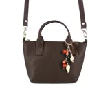Cartera mini tote de cuero marrón, con diseño compacto y líneas modernas. Cuenta con doble asa de mano, correa larga regulable y extraíble, cierre superior y un dije decorativo con cuentas de colores.