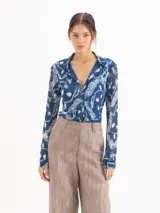 Camisa de mesh elastizado color azul con estampado de cadenas, de manga larga y suave transparencia, con drapeado en el centro delantero.