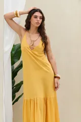 Vestido largo mostaza de lino, con tirantes finos, escote en V con abertura frontal y detalle de volado en el ruedo.