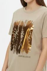 Remera de manga corta de algodón en color blanco, con cuello redondo y diseño holgado. Cuenta con un estampado frontal central con detalles metalizados estilo foil.