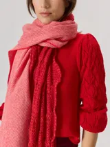 Bufanda de gran tamaño en color mostaza con diseño de tejido en espiga y flecos en los extremos. Incluye una etiqueta metálica decorativa en una de las esquinas.
