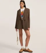 Blazer de mujer color marrón, de corte sastre alargado, con solapa ancha, cierre de doble botonadura y bolsillos tipo cuchillo.