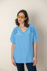Blusa celeste de lino con escote en V, mangas cortas y detalle de bordado calado en el canesú.