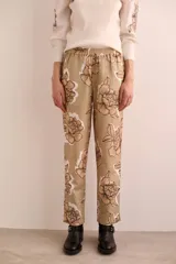 Pantalón de lino y algodón color beige con estampado de flores marrones, corte recto, bolsillos y elástico en la cintura.