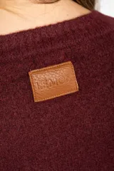 Sweater de tejido de punto color bordó, con cuello redondo, mangas largas y puños acanalados. Presenta un diseño de corte recto y textura suave.
