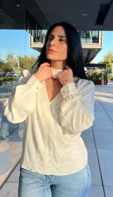 Blusa de satén color verde, con cuello en V y detalle de lazo integrado al cuello. Presenta mangas largas abullonadas con puños ajustados.