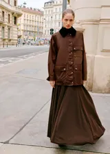Parka color marrón con efecto encerado, diseño recto y manga larga. Cuenta con cuello camisero de pana, cierre frontal de cremallera y botones a presión, múltiples bolsillos de parche con solapa y forro interior.