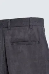 Pantalón de traje regular fit confeccionado en tejido de lino, con cierre frontal de cremallera y botón, bolsillos laterales y bolsillos traseros de vivo.