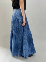 Falda larga de jean denim con efecto de lavado ácido y diseño de paneles geométricos cosidos. Presenta cintura alta, cierre lateral invisible y bolsillos ocultos, con un corte acampanado que aporta volumen y movimiento.