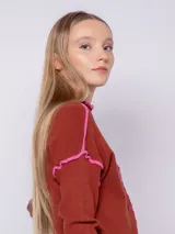 Polera de punto color beige con cuello alto, manga larga y detalles de costura overlock en color naranja.