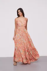 Vestido largo de tirantes finos con escote en V, diseño holgado y falda con volados en el ruedo. Presenta un estampado tipo paisley en tonos naranja y beige.