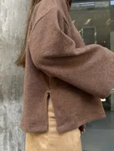 Polerón de punto color marrón, con cuello alto, mangas largas amplias y diseño holgado.
