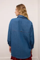 Camisa de jean oversized color azul, con botones rojos y costuras en contraste rojo. Tiene un bolsillo en el pecho.
