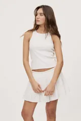 Falda corta blanca con diseño de volados escalonados y cintura elastizada, de silueta fluida y liviana.
