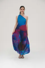 Vestido largo de fiesta con estampado abstracto en tonos azules, fucsia y violetas. Diseño de un solo hombro y falda con suave transparencia.